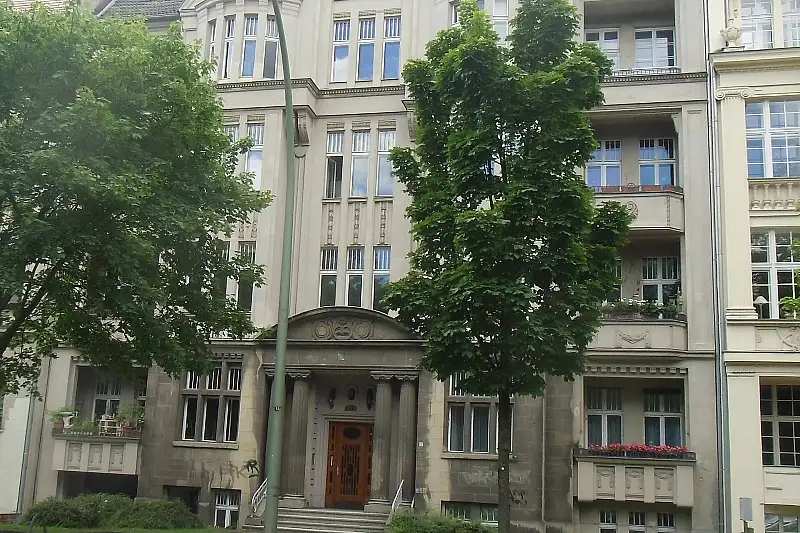 Altbau-Hauseingang mit rundbogigem Portal und roter Holztür eines Gründerzeit-Mietshauses in Berlin