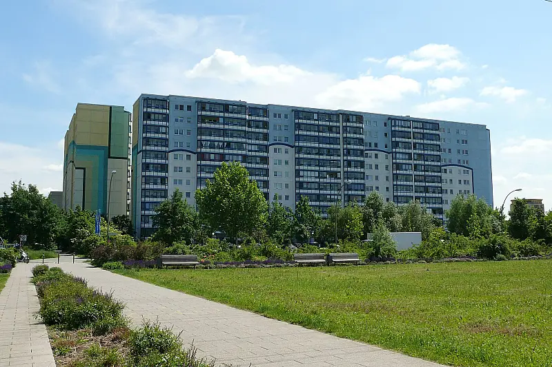 Plattenbau-Wohnblock mit grüner Vorfläche und Fußweg, aufgenommen im Kosmosviertel in Altglienicke